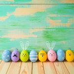 Easter eggs decorations on wooden table over colorful background
